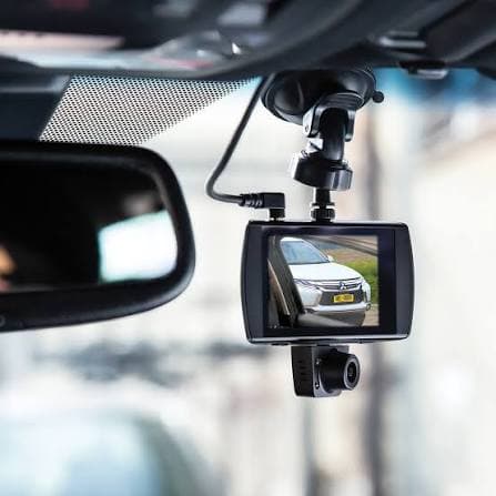 Black dashcam mounted on a car windshield, displaying a white car on its screen.